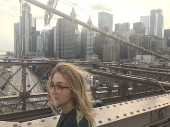 Woman with tousled hair standing on bridge in city