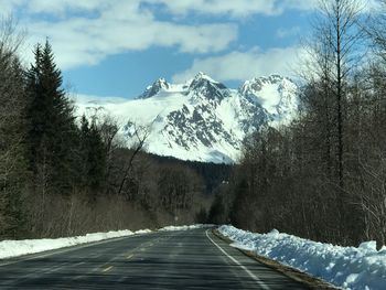 Road amidst trees against sky during winter