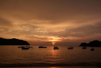 Silhouette boats moored on sea against sky during sunset