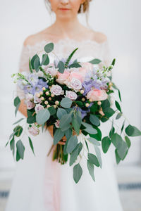 Midsection of woman with pink flower bouquet