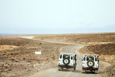 Vintage car on desert land against sky