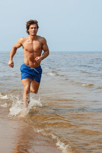 Shirtless man standing at beach