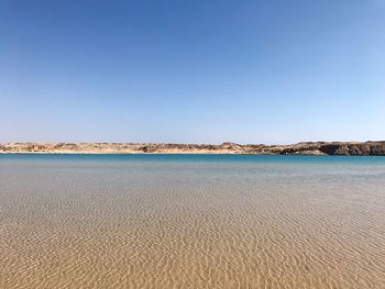 Scenic view of beach against clear blue sky