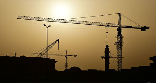 Low angle view of silhouette crane against sky during sunset