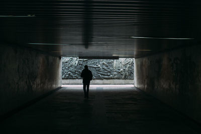 Rear view of man walking in tunnel