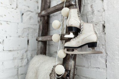 Close-up of ice skate hanging on ladder against wall