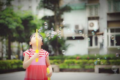 Girl making bubbles from wand in back yard