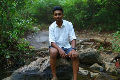 Portrait of young man sitting in forest