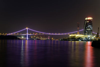 Illuminated bridge over river at night