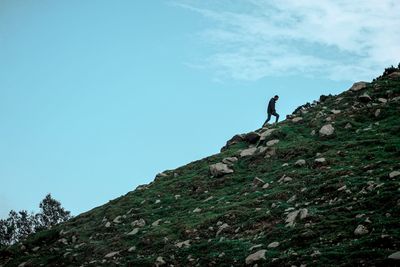 Low angle view of man walking on rock against sky