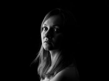 Portrait of woman against black background