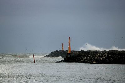 View of factory by sea against clear sky