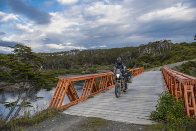 Man on off road touring motorbike crossing wooden bridge