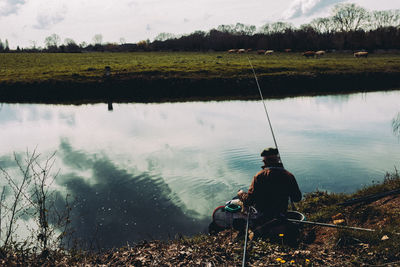 Rear view of a man fishing at calm lake