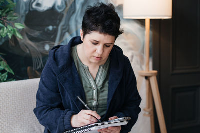 Teenage girl sitting on book at home