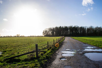 Road amidst field against sky