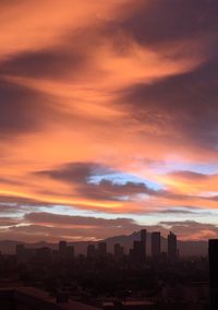 Cityscape against dramatic sky at sunset