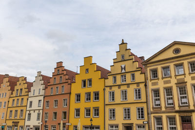 Low angle view of buildings against cloudy sky