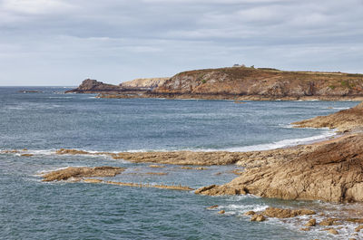 Scenic view of sea and cliff against sky