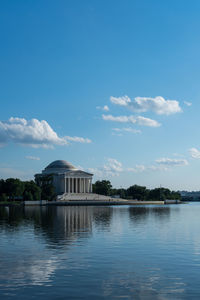 View of building by lake against cloudy sky