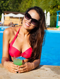 Portrait of young woman wearing sunglasses at swimming pool