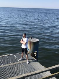Portrait of young man standing in sea against sky