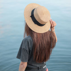 Rear view of woman wearing hat looking at sea