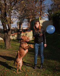 Full length of teenage girl with dog against trees