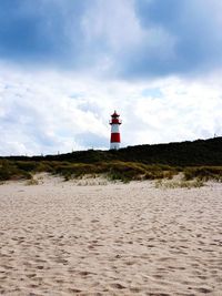 Lighthouse by street amidst buildings against sky