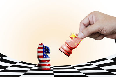 Low angle view of person holding chess board against white background