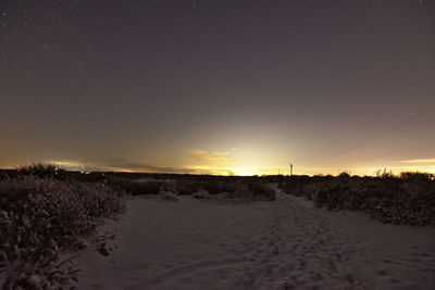 Scenic view of snowy field against sky at sunset