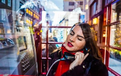 Portrait of smiling young woman in city at night