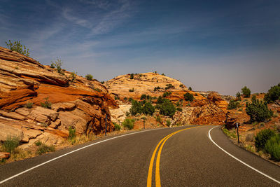 Road leading towards rock formation against sky