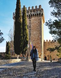 Woman standing by historic building against sky