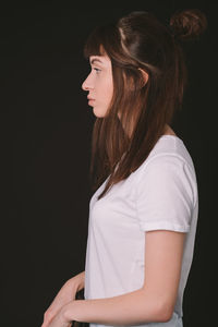 Side view of beautiful young woman against black background