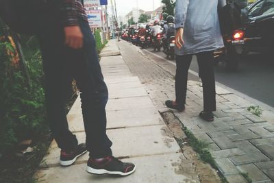 Low section of men standing on sidewalk in city