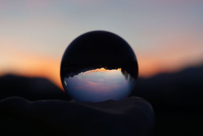 Close-up of silhouette crystal ball against sky during sunset