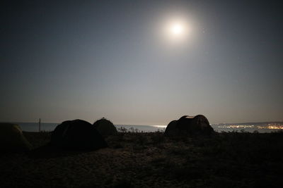 Silhouette rocks on field against sky at night