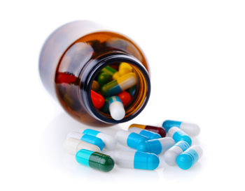 Close-up of pills with bottle on white background