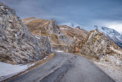 Road amidst snowcapped mountains against sky