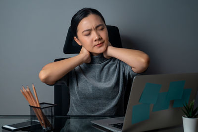 Young woman using mobile phone while sitting on table