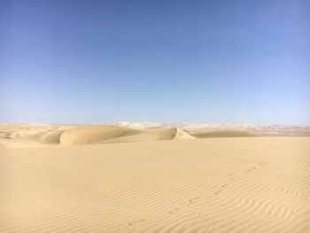 Sand dunes in desert against clear blue sky