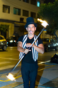 Portrait of cheerful man performing with fire on street at night