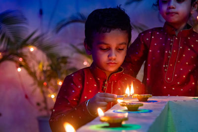 Portrait of smiling young boy with illuminated diwali diyas