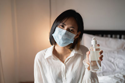 Portrait of young woman holding hand sanitizer