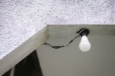 Low angle view of light bulb against white wall