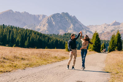Cheerful couple standing on road against mountains