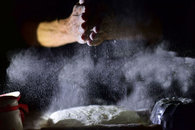 Close-up of person preparing food against black background