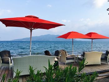 Red chairs on beach against sky