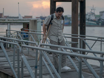Full length of man standing on railing against sky